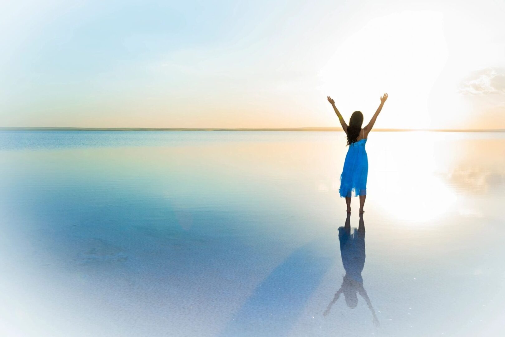 A woman standing on the beach with her arms in the air.